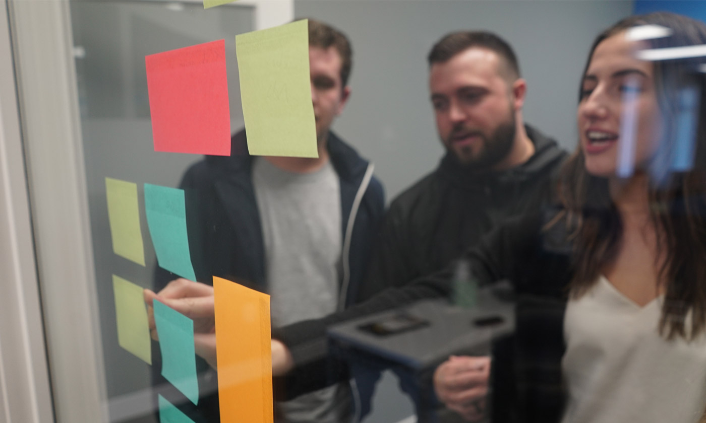 team looking at sticky notes on the glass wall