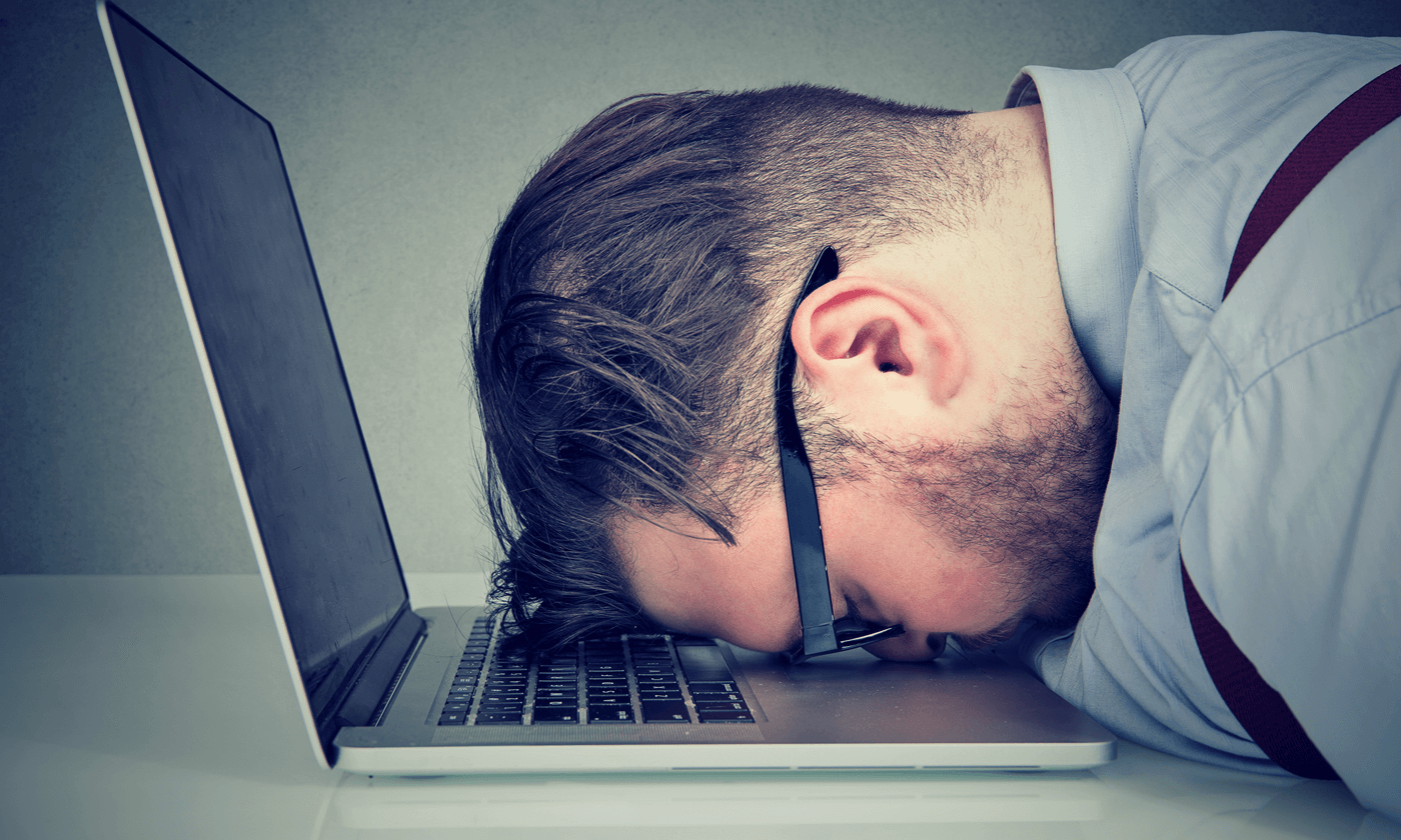 man on his head down in front of a laptop