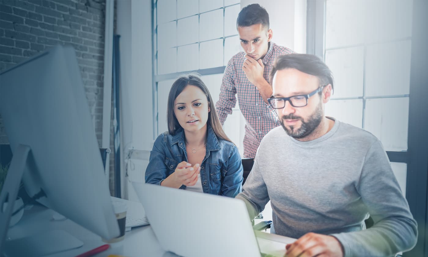 man working on a laptop while other people looking