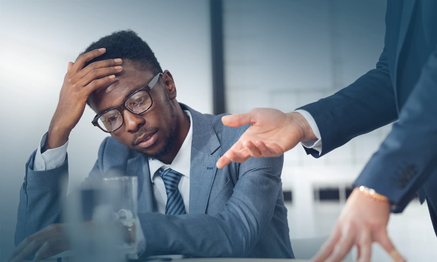 man touches forehead while listening to the other man