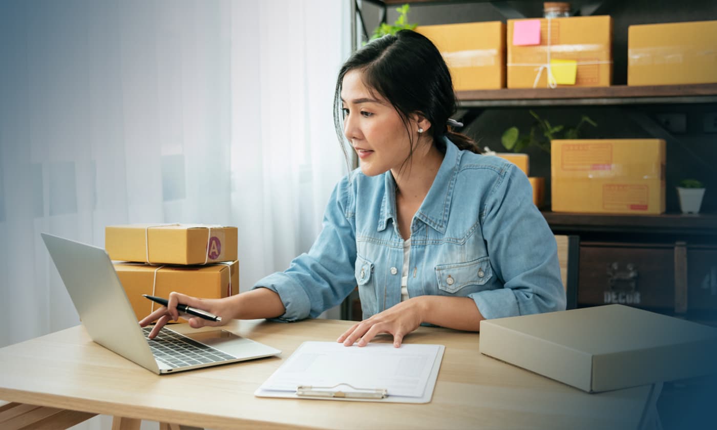 small business owner using computer near shipping boxes