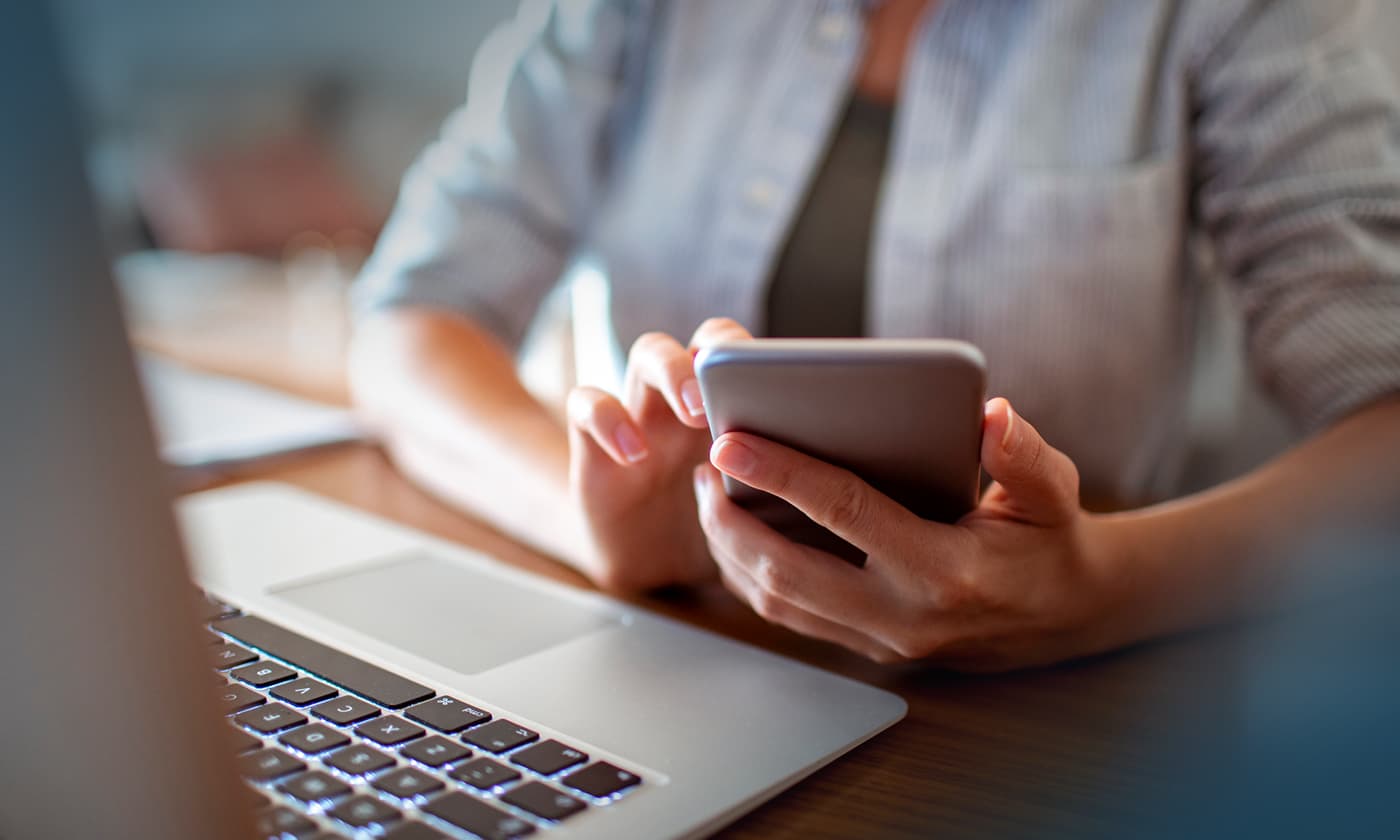 woman on computer with cell phone