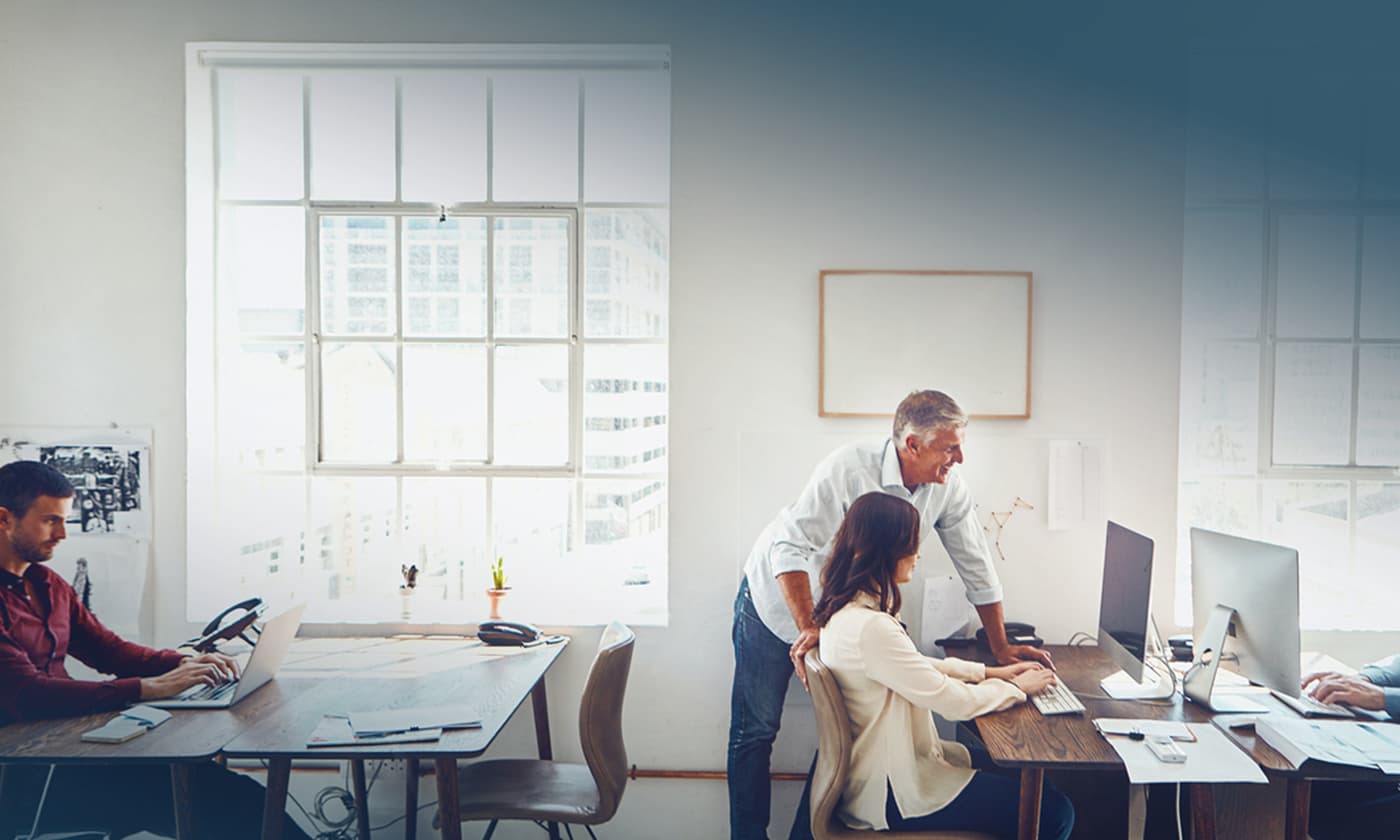 well lit office showing workers engaged at computers at various workstations