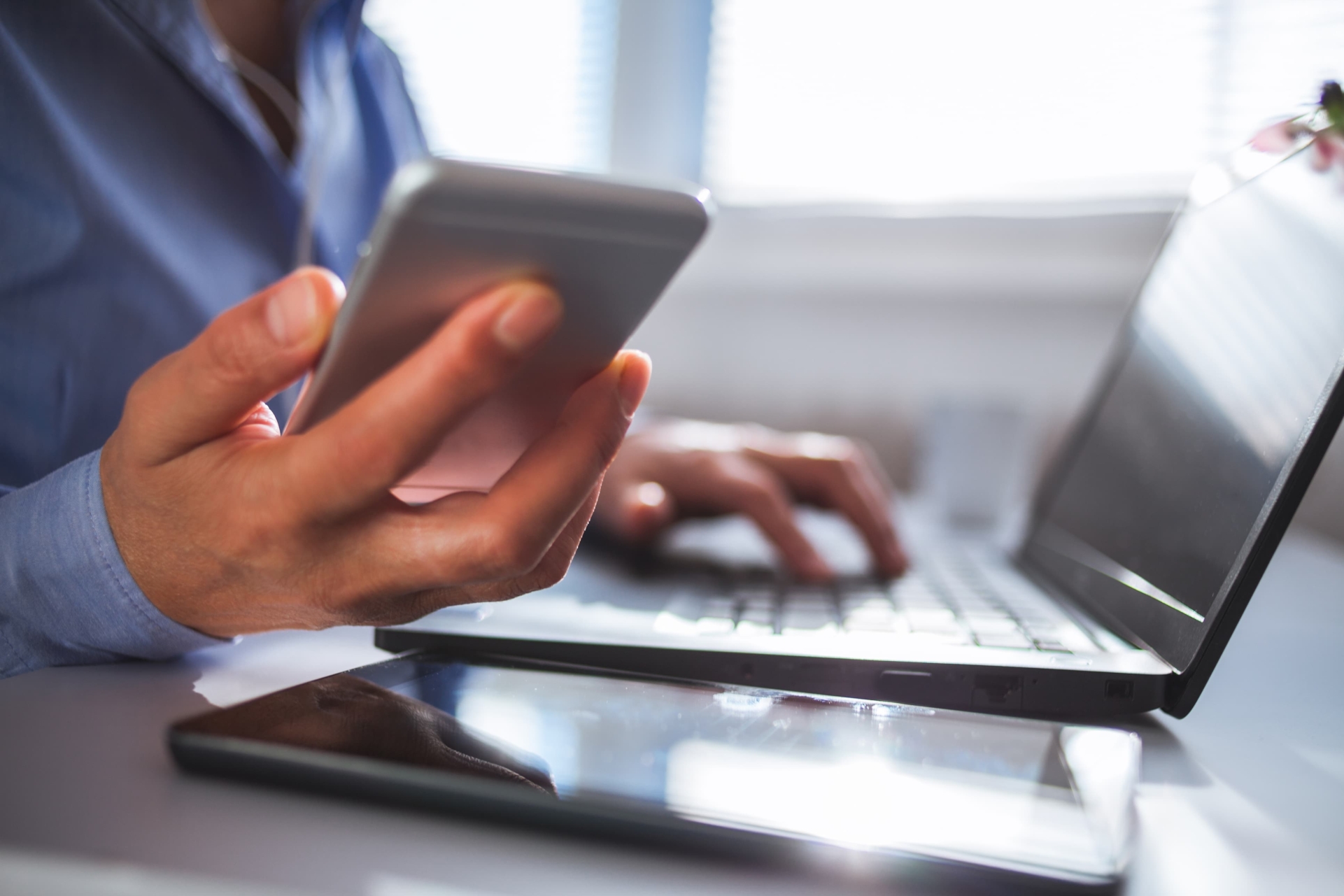 Person sitting at a laptop with a cell phone