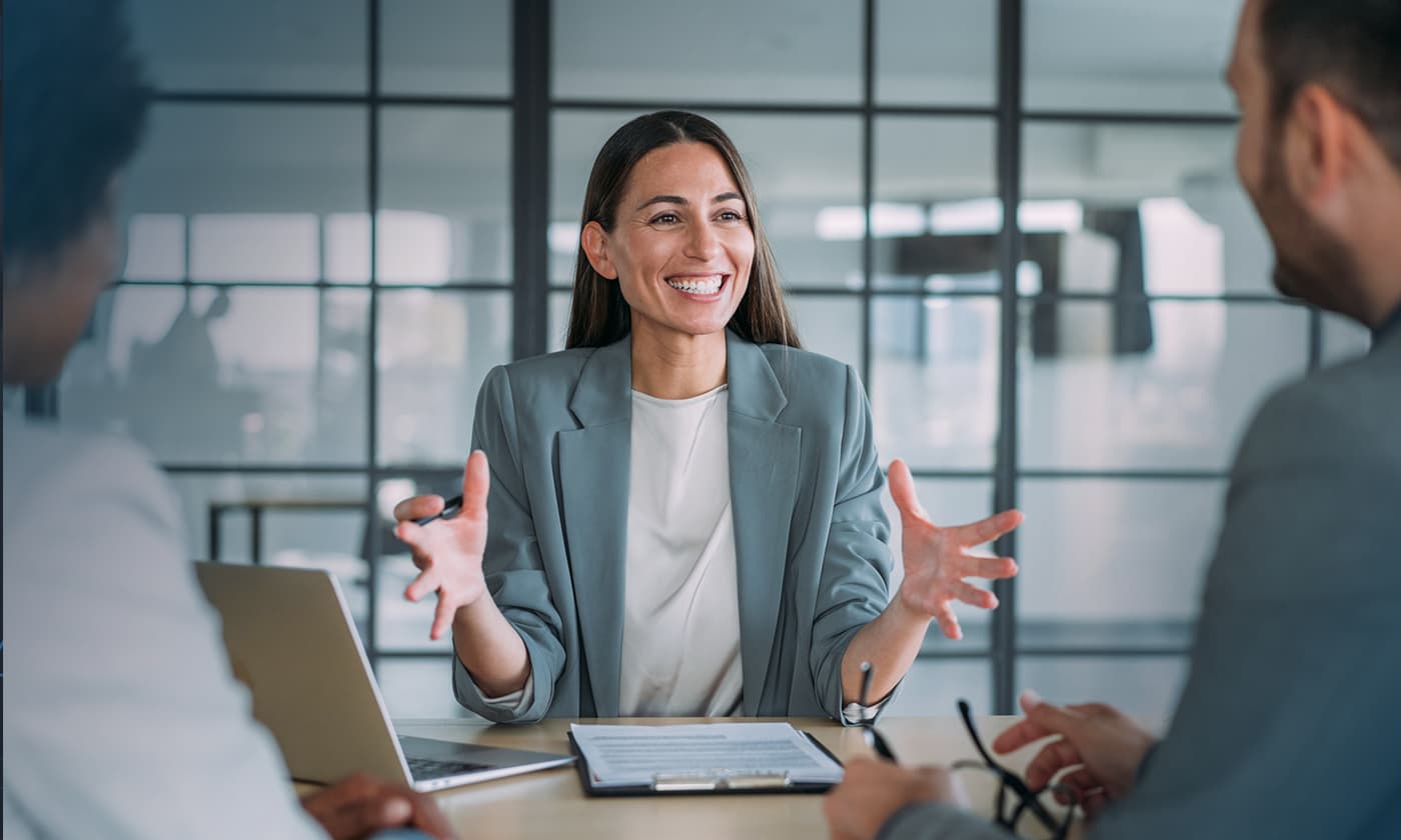 woman having discussion with others at desk in office setting